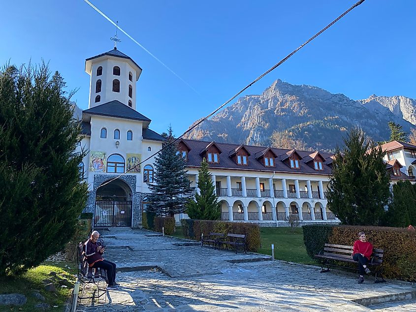 A large white monastery stands in front of a craggy mountain