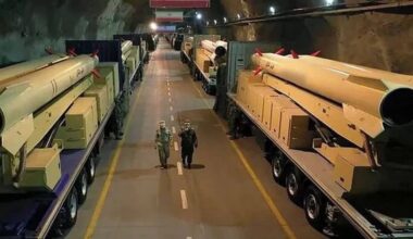IRGC aero-space personnel walk past transporter-erector-launchers carrying ballistic missiles inside an underground tunnel facility