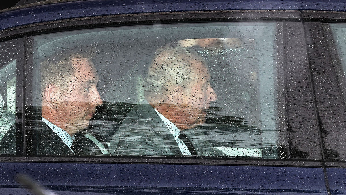 King Charles inside a car on a rainy day.