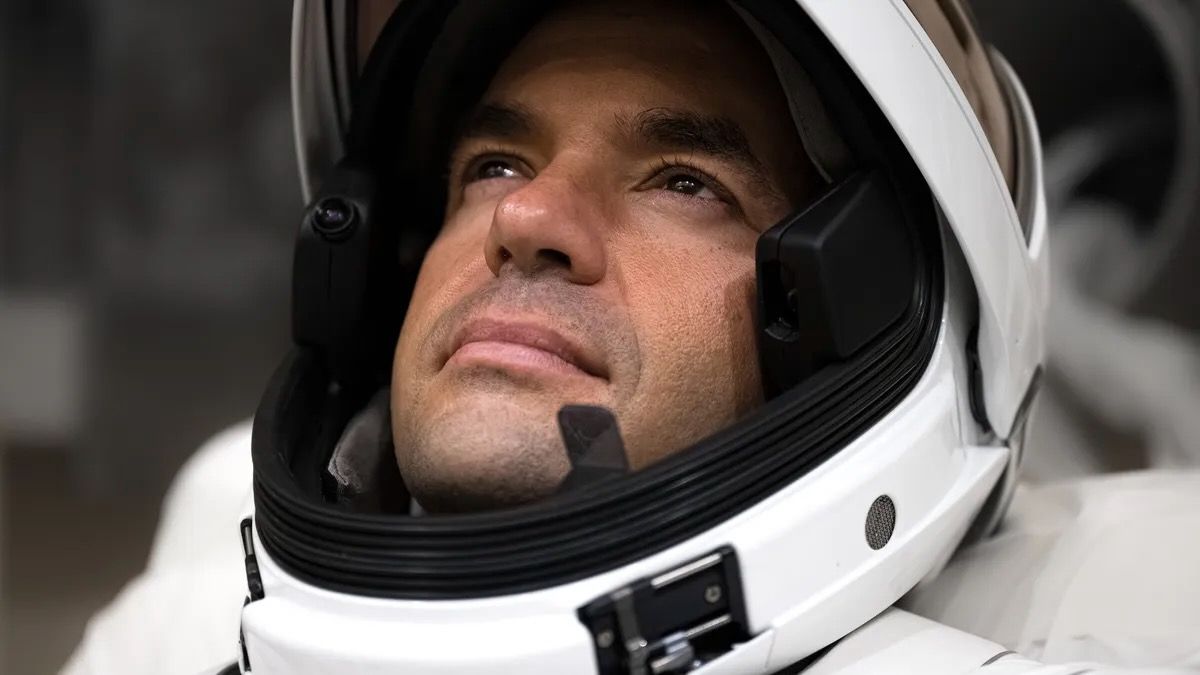 head shot of a male astronaut wearing a white spacesuit helmet