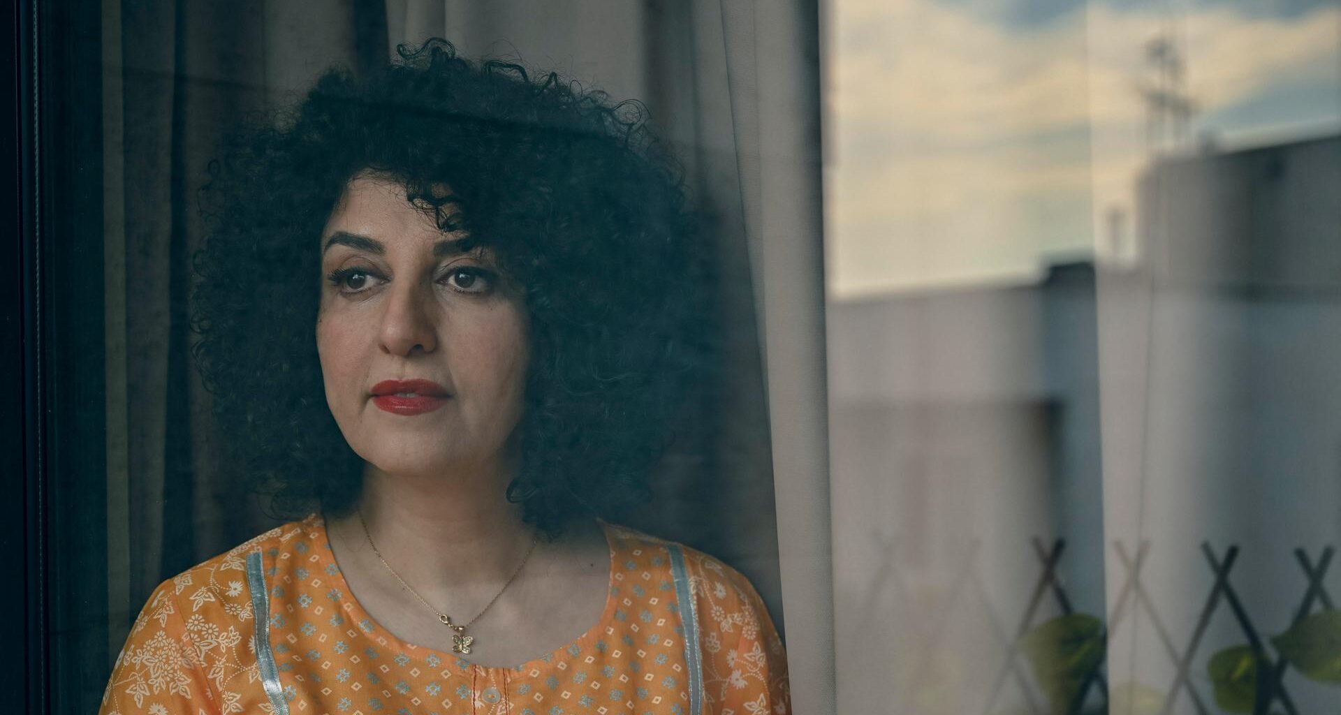 Die Friedensnobelpreisträgerin Narges Mohammadi steht mit gelber Bluse vor einem Fenster.