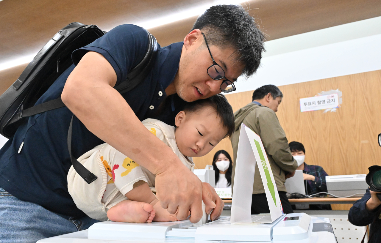 A voter casts an early ballot with a child at an early voting station inside the Jungnim-dong Community Service Center in Jung-gu, Seoul, on May 29, the first day of early voting for the 21st presidential election. Im Se-jun/The Korea Herald
