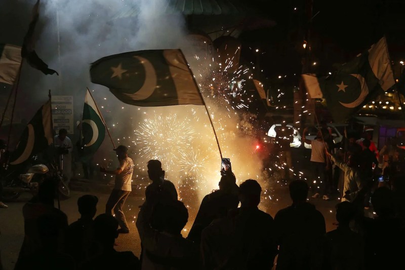 Pakistanis wave the national flag as they celebrate after the cease-fire between Pakistan and India, in Hyderabad, Pakistan, on May 10.