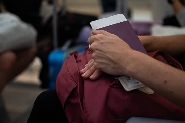 Person holding a passport and backpack while waiting in an airport, suggesting travel or border processing.