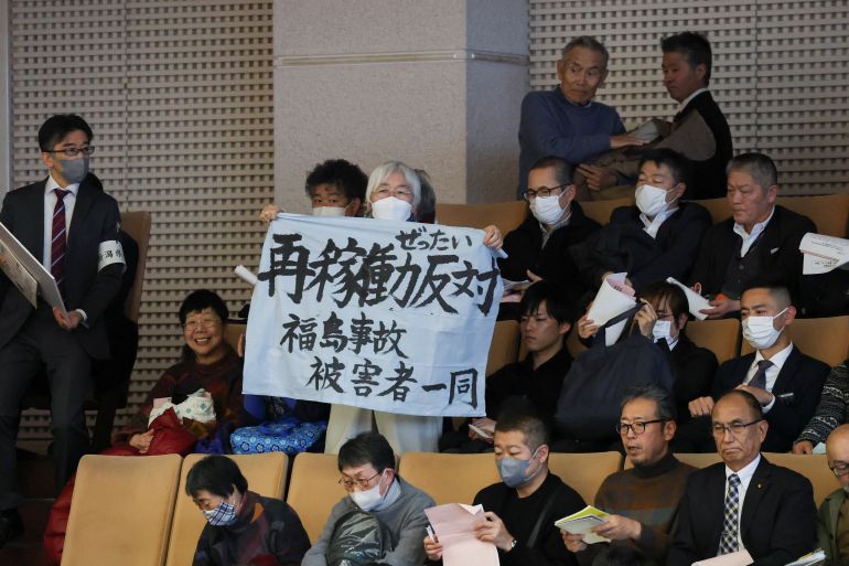 A woman holds a banner that reads, "Against Restart" near auditors seated on the day Niigata Prefectural Assembly lawmakers take part in a vote of confidence in the prefectural governor's decisions on a partial restart of the Tokyo Electric Power Company's (TEPCO) Kashiwazaki Kariwa Nuclear Power Plant, one of the world's largest nuclear power plants and which was among the reactors shut after a massive earthquake and tsunami in 2011 crippled TEPCO's Fukushima Daiichi plant, in Niigata, Japan December 22, 2025. REUTERS/Issei Kato
