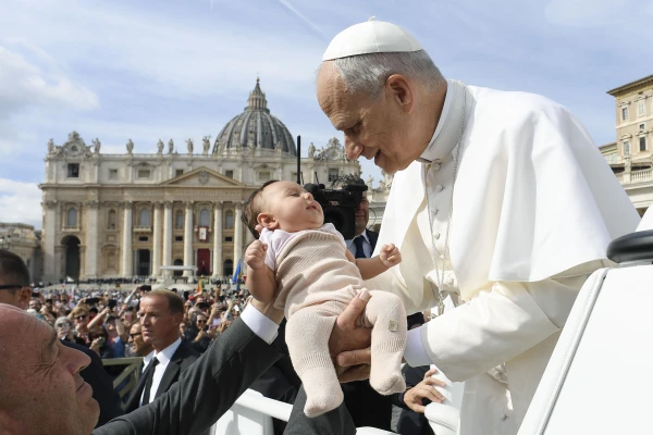 Pope Leo XIV pauses to embrace a baby in the crowd during Sunday Mass in St. Peter’s Square on Oct. 12, 2025. Credit: Vatican Media