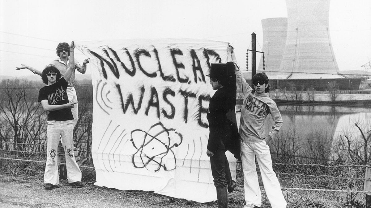 Four protesters stand holding a banner reading 