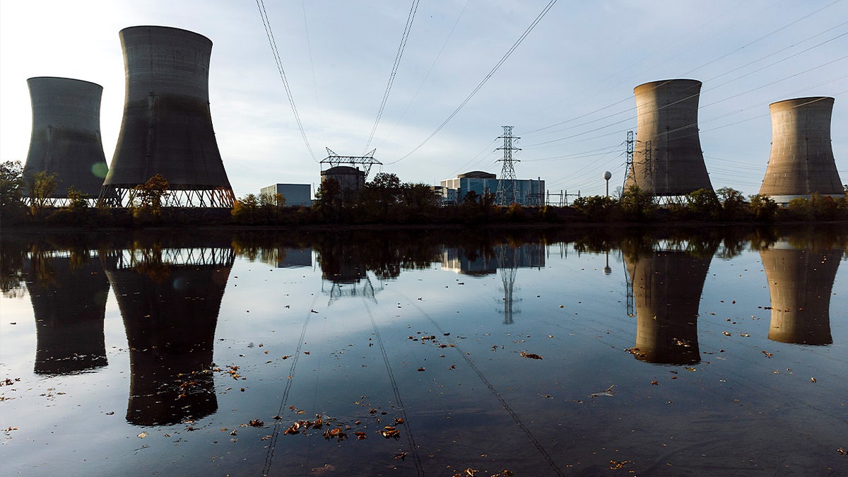 Cooling towers from the former Three Mile Island nuclear plant rise above the Susquehanna River, with two towers inactive after a past meltdown.