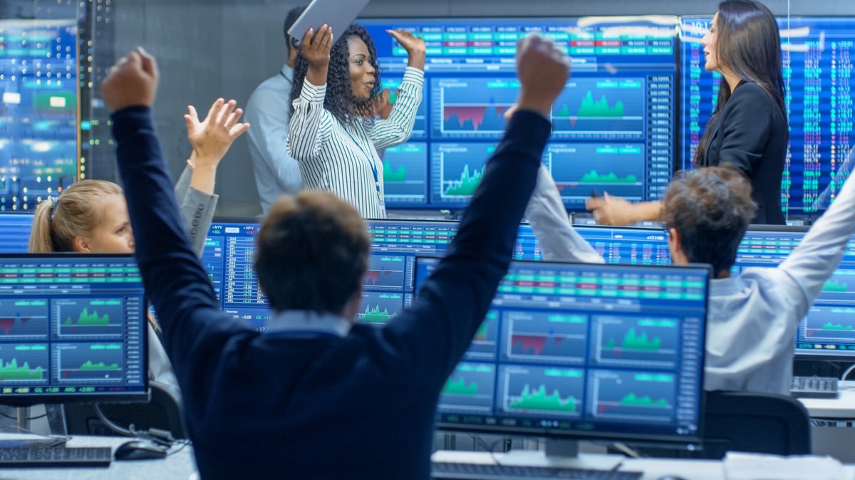 Wall Street traders looking at graphs and charts, cheering because the stock market went up.