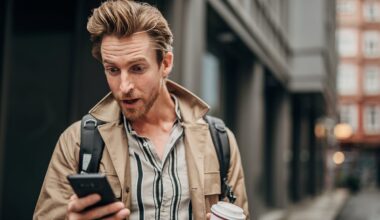 Person on street, staring at phone with surprised look.