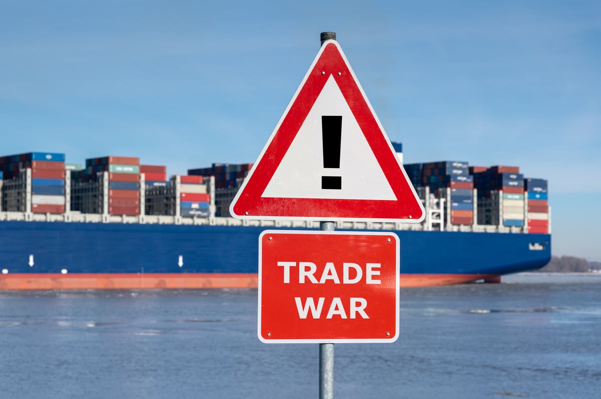 A picture of a container ship behind a sign that says "Trade War."