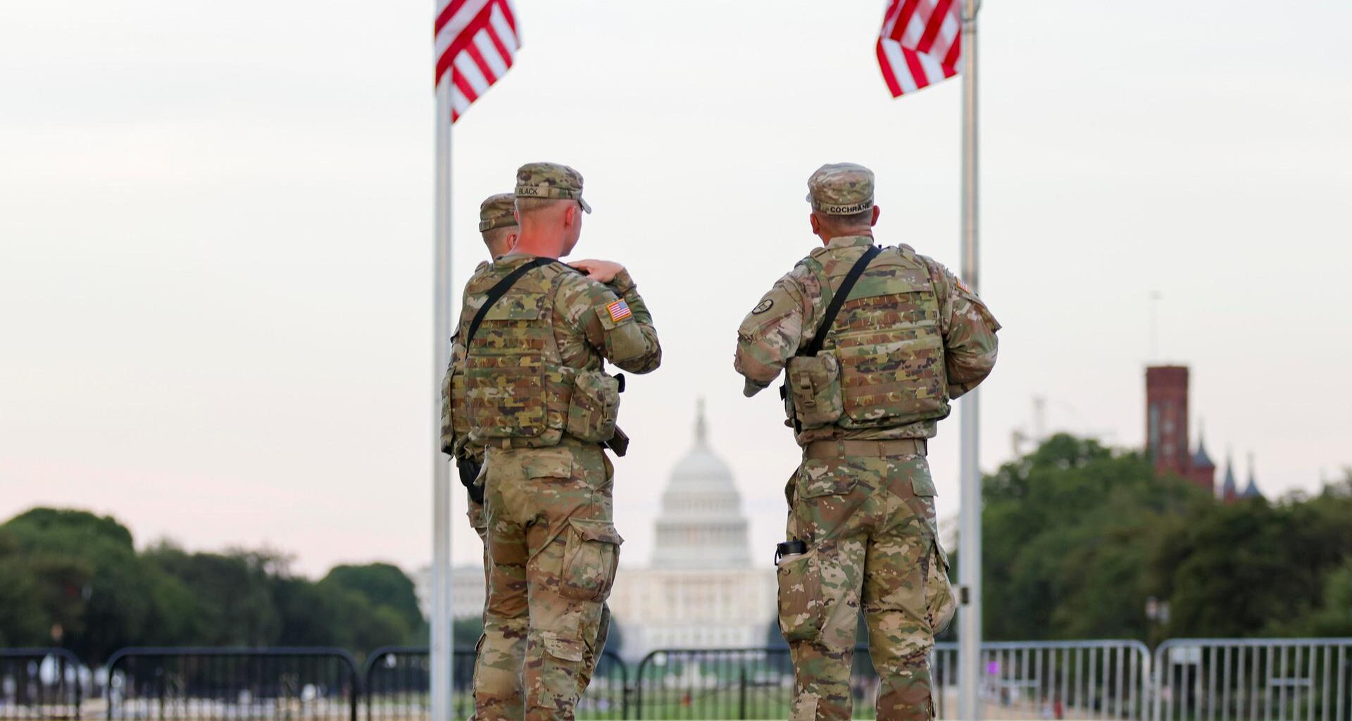 Zwei Soldaten der US National Guard stehen in Washington unter zwei US-Flaggen