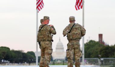 Zwei Soldaten der US National Guard stehen in Washington unter zwei US-Flaggen