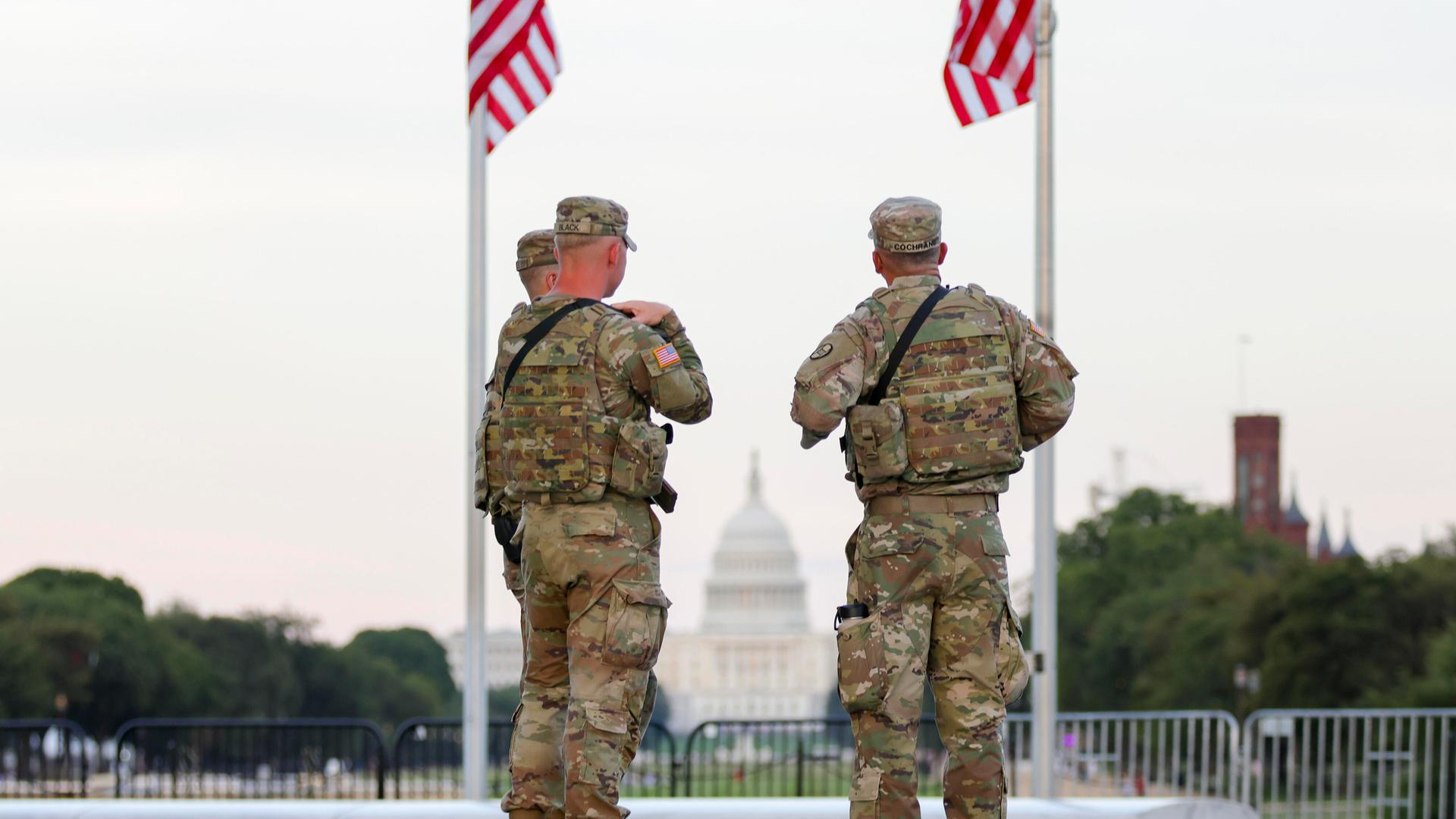 Zwei Soldaten der US National Guard stehen in Washington unter zwei US-Flaggen