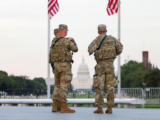 Zwei Soldaten der US National Guard stehen in Washington unter zwei US-Flaggen Zwei Soldaten der US National Guard stehen in Washington unter zwei US-Flaggen