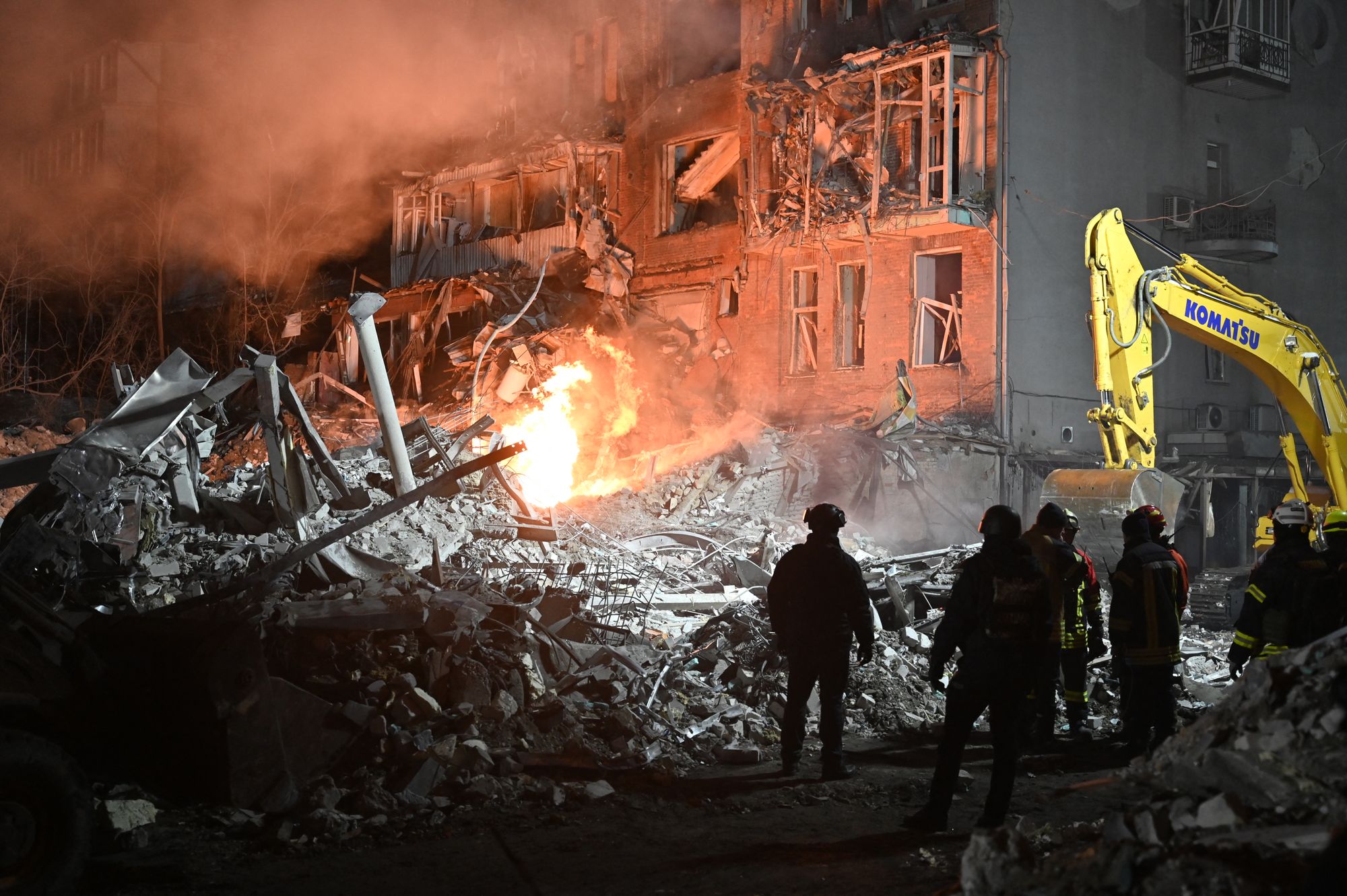 Firefighters and emergency workers look towards a damaged residential building following a air strike in Kharkiv on 2 January 2026