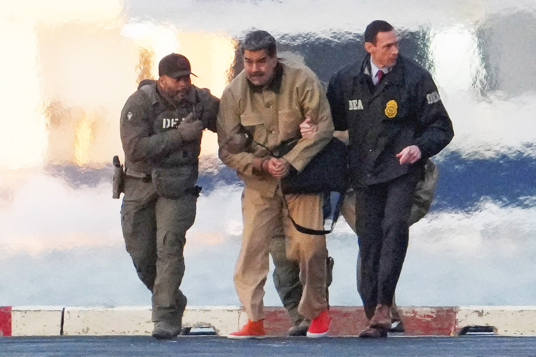 Venezuelan President Nicolas Maduro, handcuffed, being escorted by DEA agents.