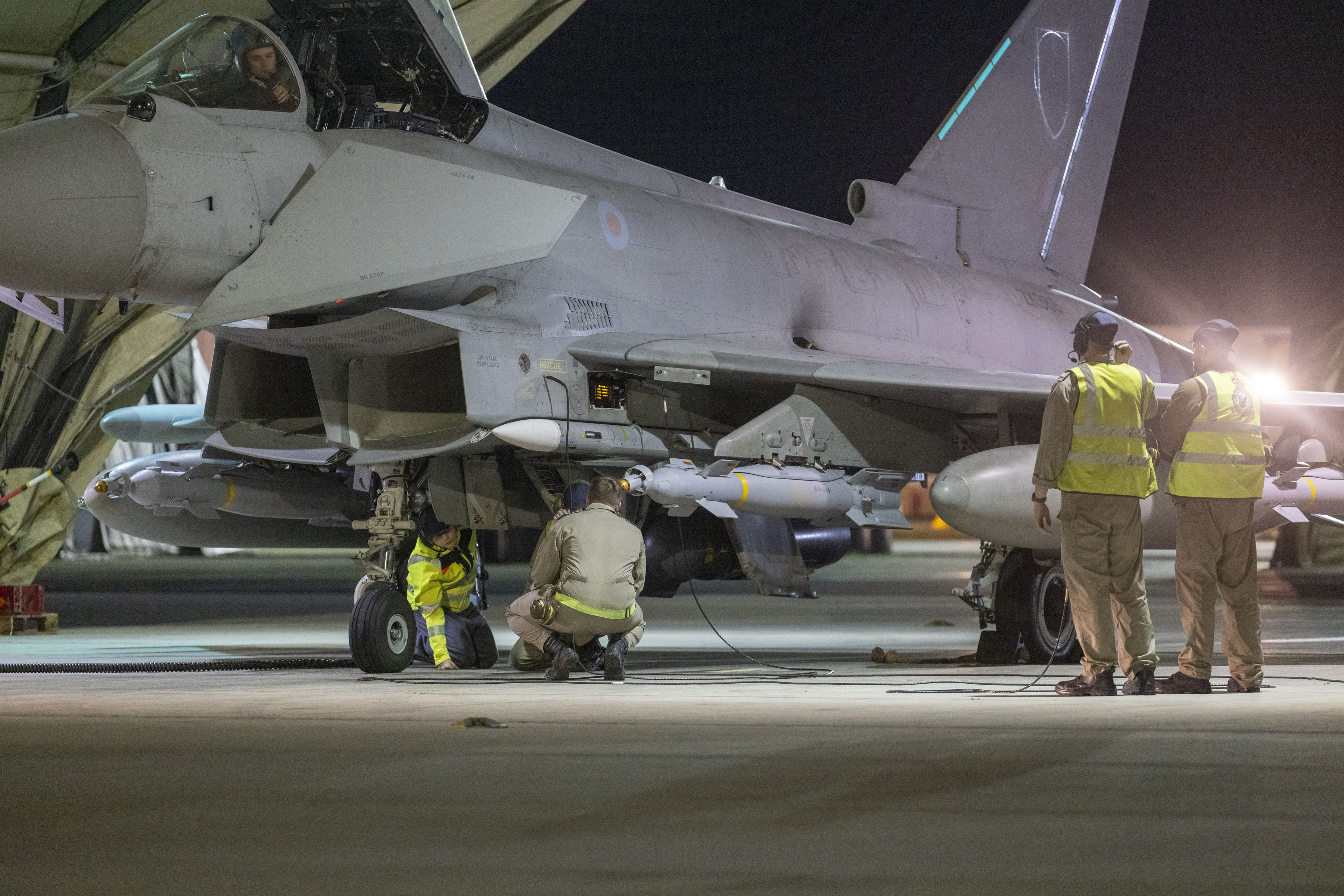 Royal Air Force personnel preparing a Typhoon aircraft with missiles for takeoff.