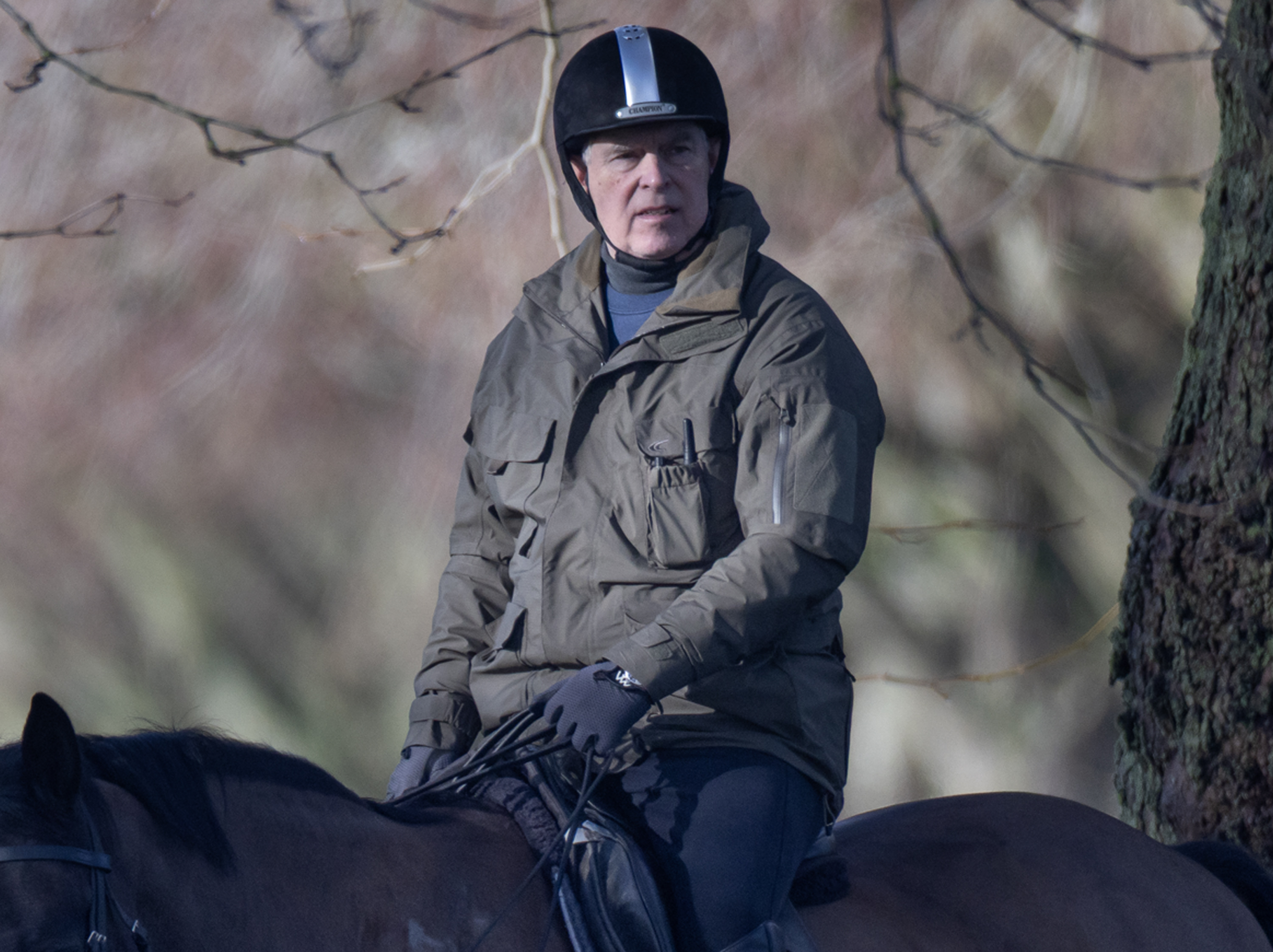 Andrew Mountbatten-Windsor on horseback, wearing a helmet and a khaki jacket with a walkie-talkie in his breast pocket.