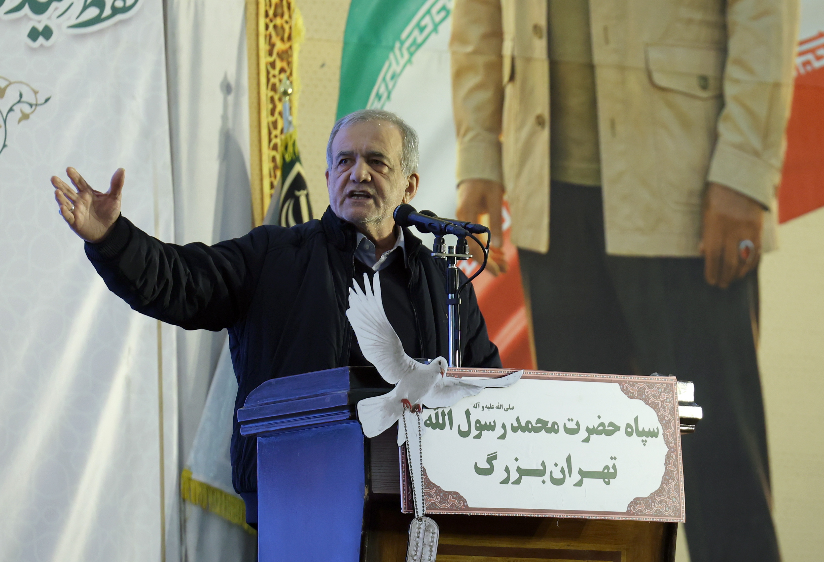 Iranian President Masoud Pezeshkian speaking at a podium with a white dove decoration during a commemoration ceremony.