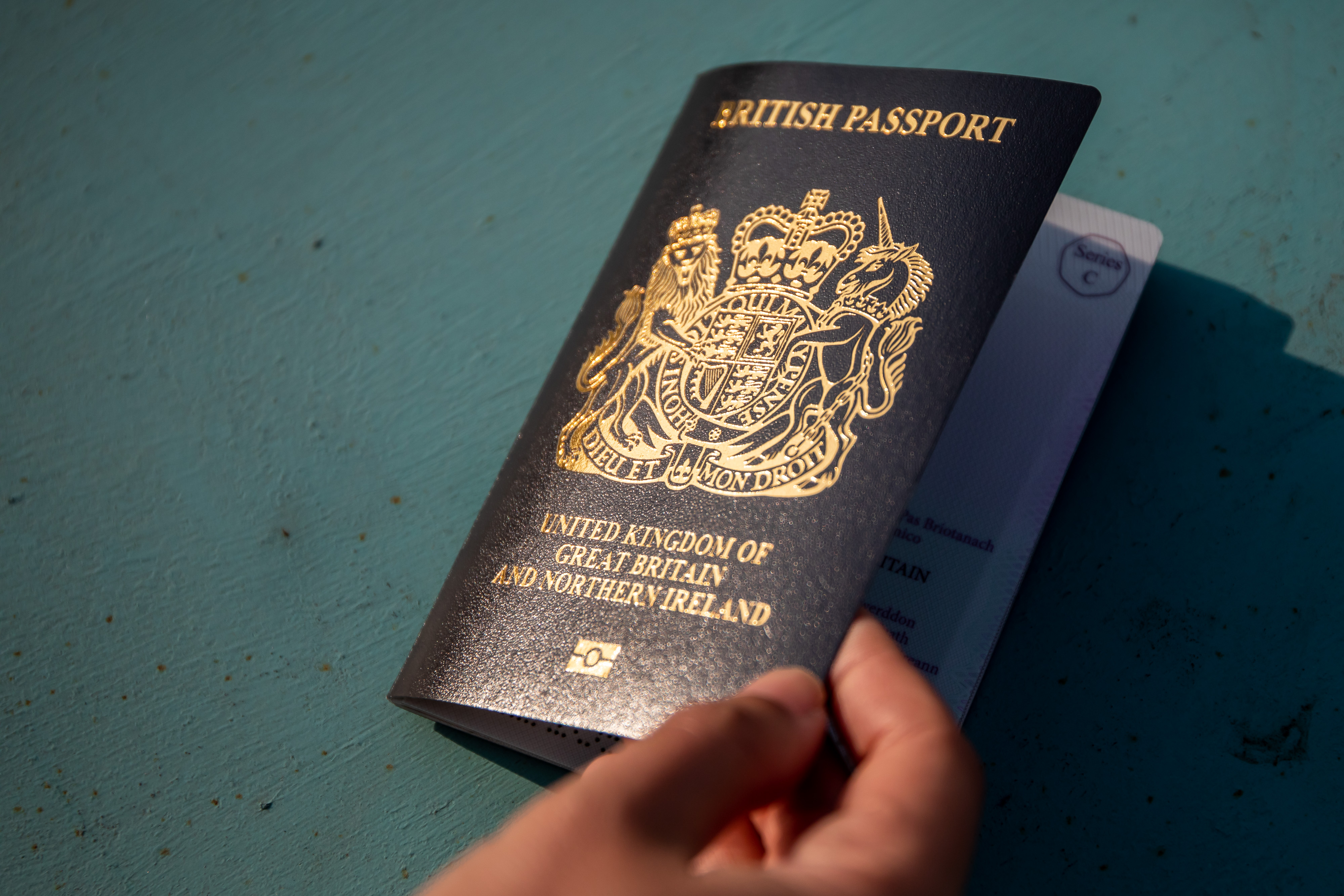 A hand holds a British National (Overseas) passport.