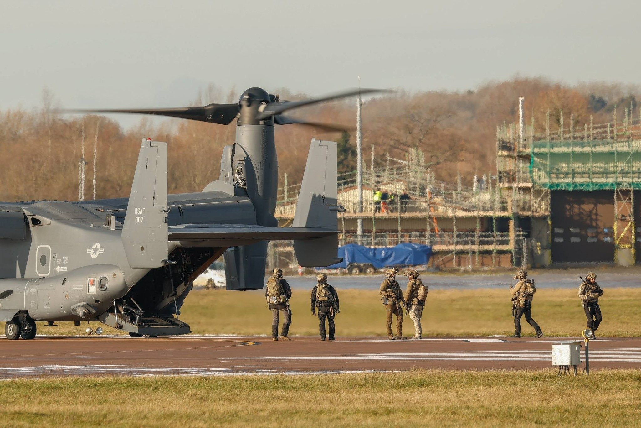 USAF CV-22B Osprey Tiltrotor Military Aircraft on a runway with five special operations personnel nearby.