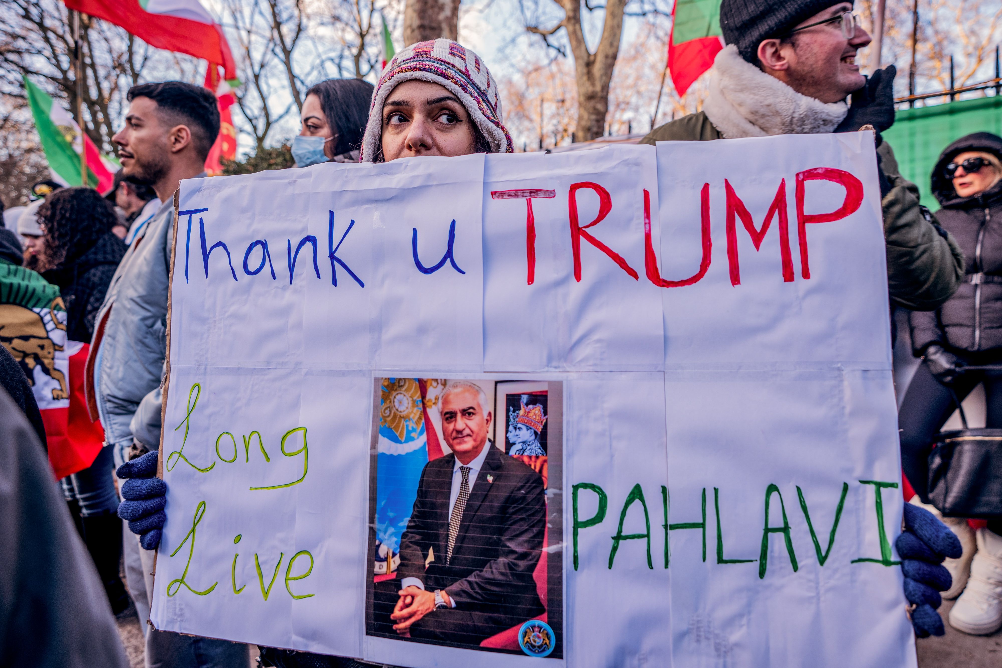 A protestor holds a sign thanking Trump and calling for the return of Crown Prince Reza Pahlavi.