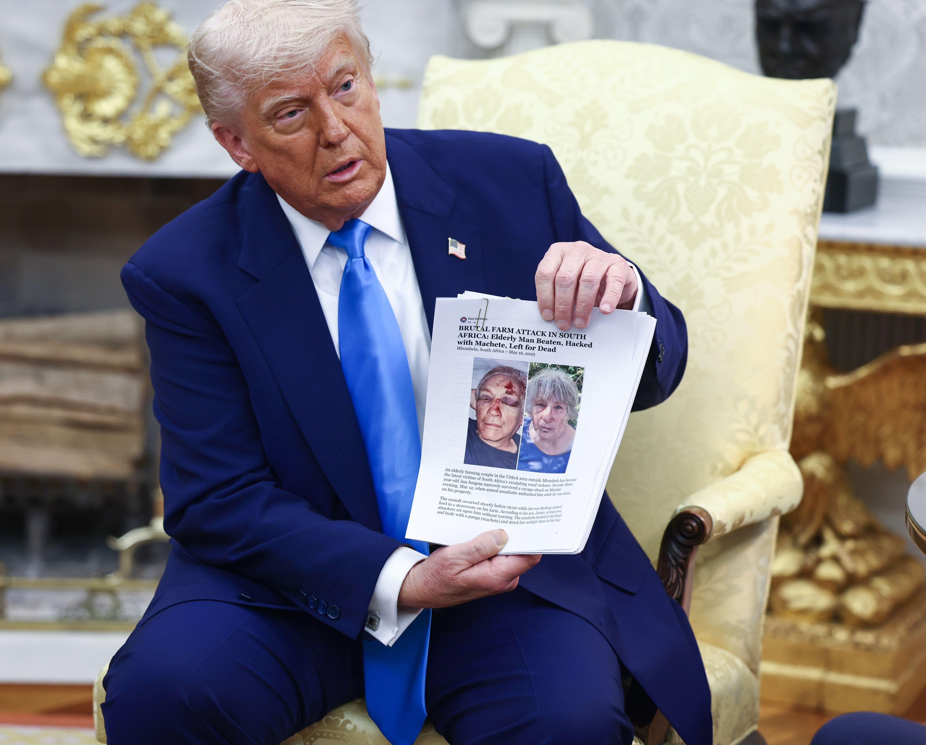 United States President Donald J Trump holds up news articles related to violence in South Africa.