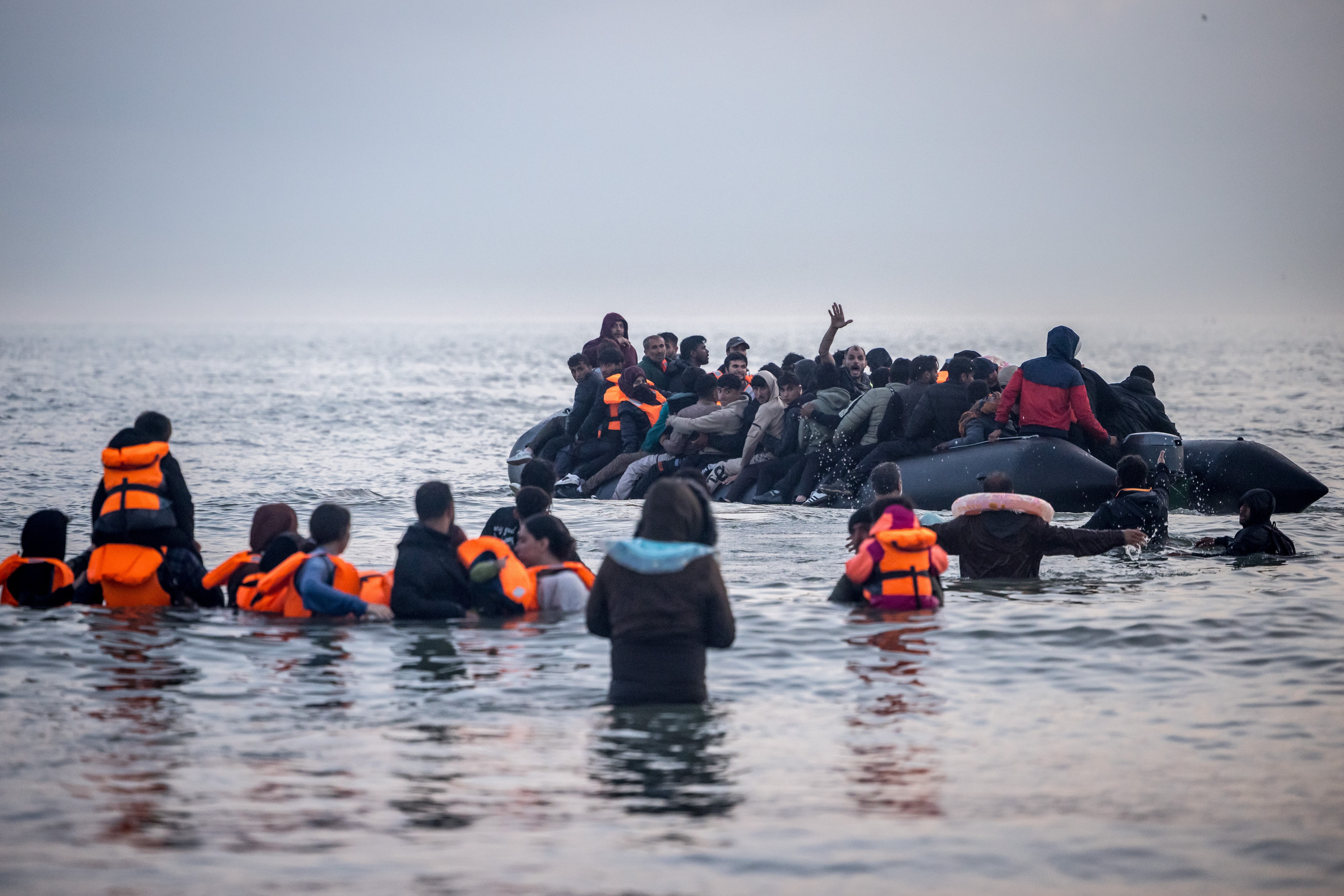 Migrants in the water and aboard a dinghy attempting to cross the English Channel.