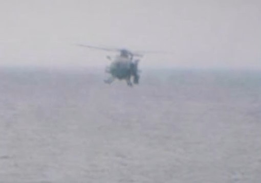 Helicopter flying over water.