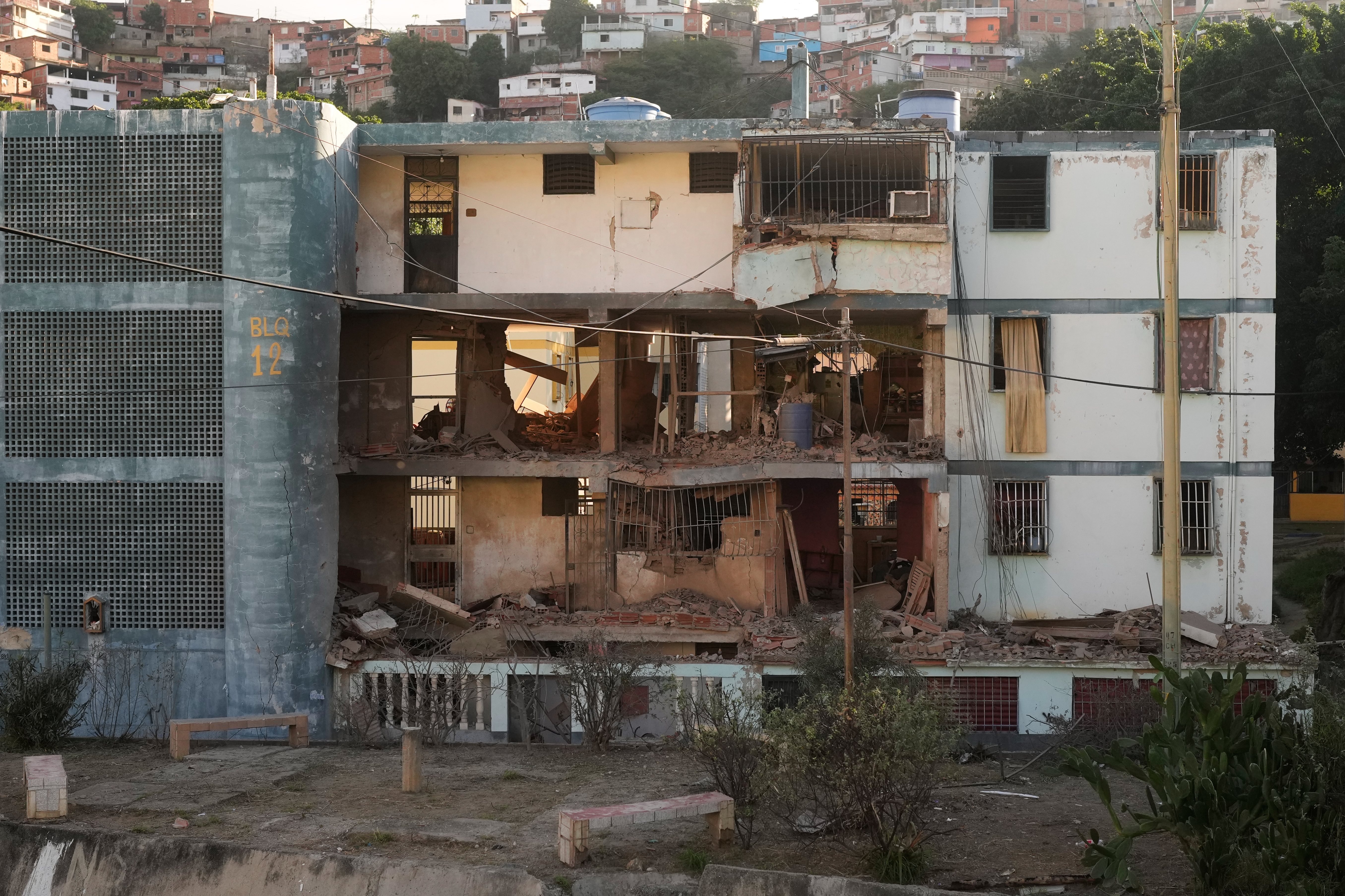 A damaged apartment complex in Catia La Mar, Venezuela, with the front wall of multiple units missing, exposing the rubble and interiors.