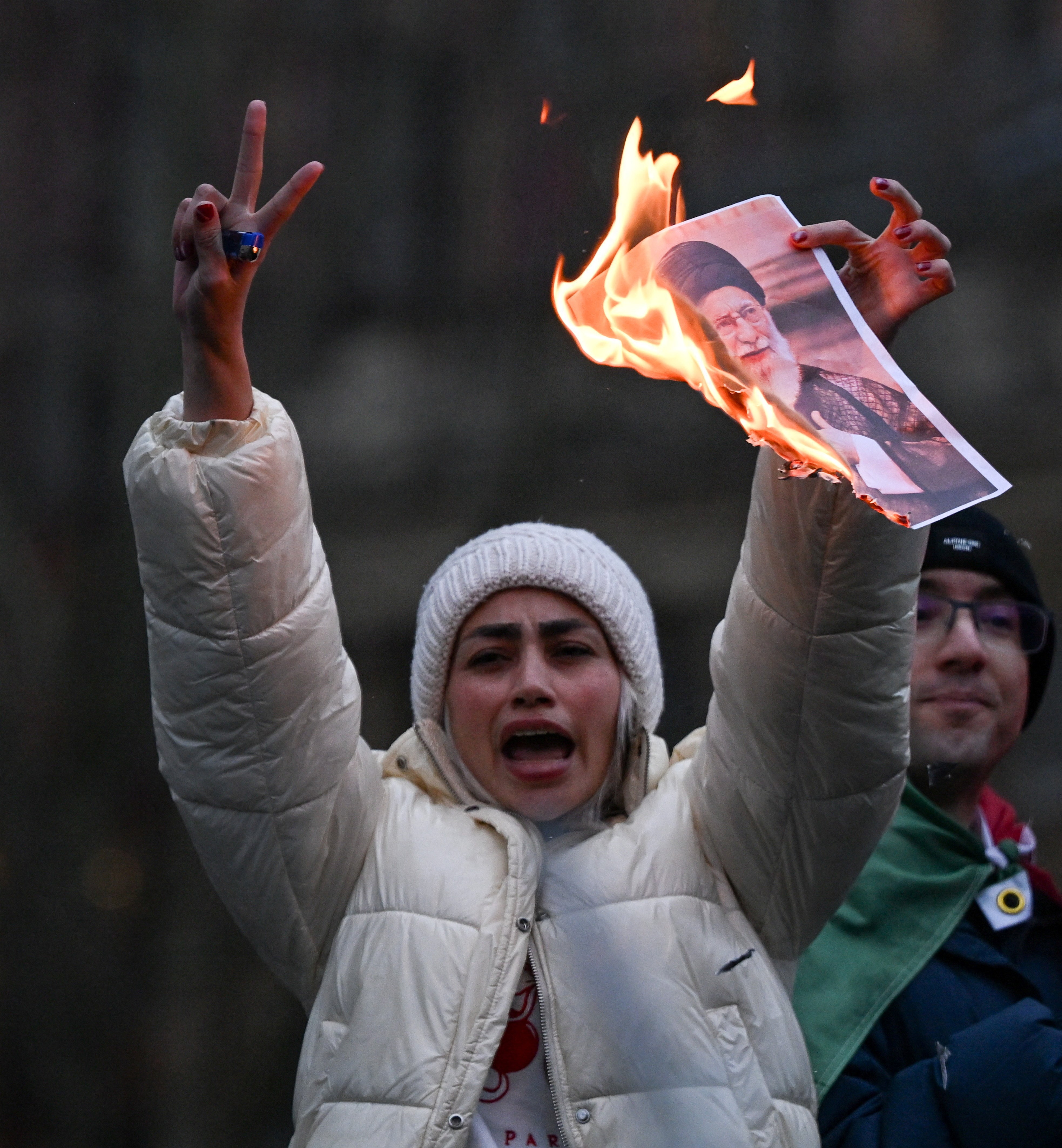A demonstrator holds a burning photo of Iran's Supreme Leader Ayatollah Ali Khamenei during a protest in London.