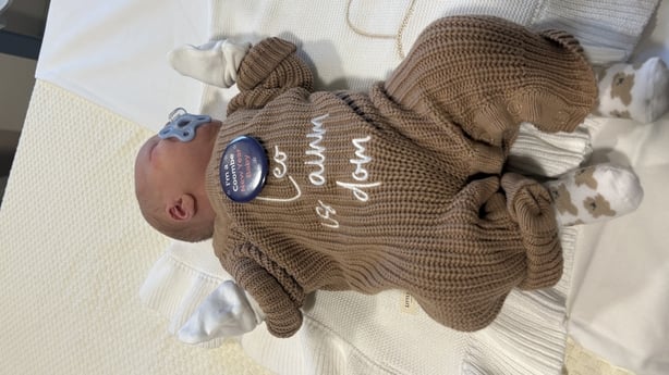 a newborn baby wearing a onsie with the words 'Leo is anam dom' 