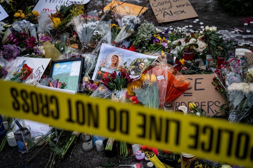 Photos of Nicole Good and Alex Pretti are placed among flowers at a makeshift memorial in the area where Pretti was shot and killed by federal immigration agents, in Minneapolis, Minnesota, on January 26, 2026.