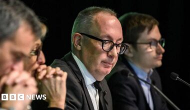 Crans-Montana Mayor Nicolas Feraud looks downward as he sits with colleagues at a press conference where he revealed the ski bar had not been checked for five years.