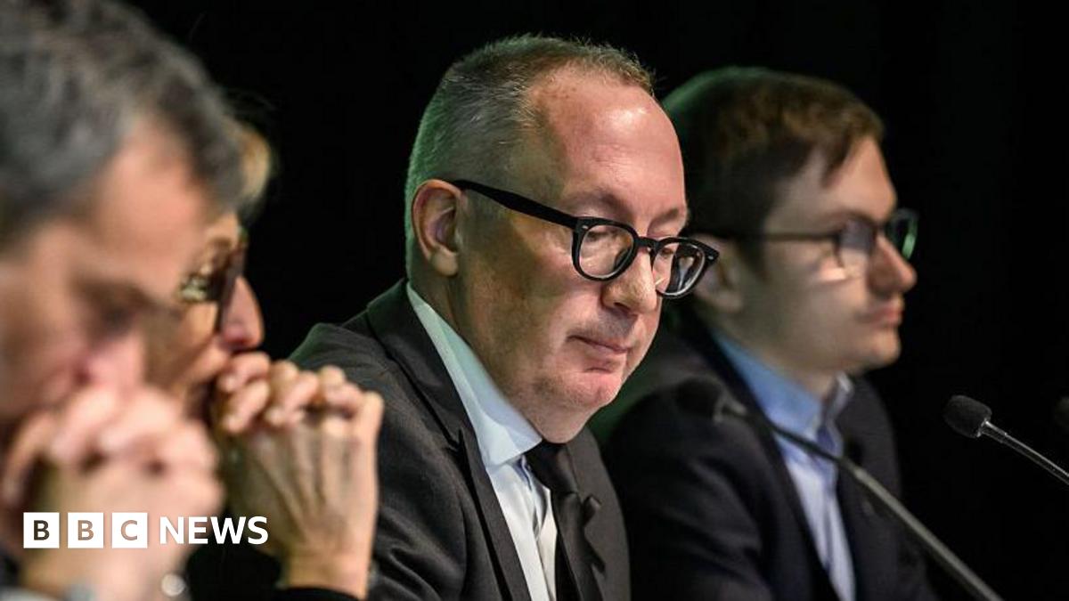 Crans-Montana Mayor Nicolas Feraud looks downward as he sits with colleagues at a press conference where he revealed the ski bar had not been checked for five years.