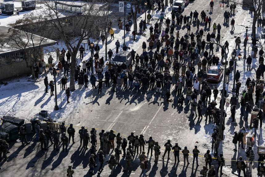 Federal agents line up opposite community members at the scene where federal agents fatally shot Alex Pretti, in Minneapolis, Minnesota, on January 24, 2026.