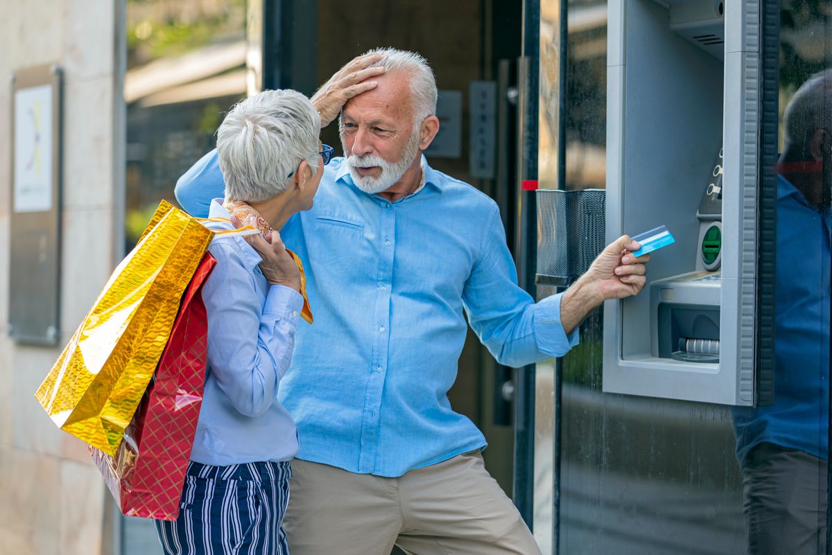 Handsome Older Man with Grey Hair and Beard is Withdrawing Money from Cash machines