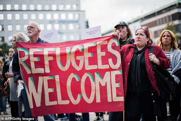 People hold a banner 'refugees welcome' as they take part in a demonstration in solidarity with refugees seeking asylum