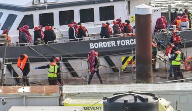 Border Force officers escort migrants into Dover Docks after helping them ashore