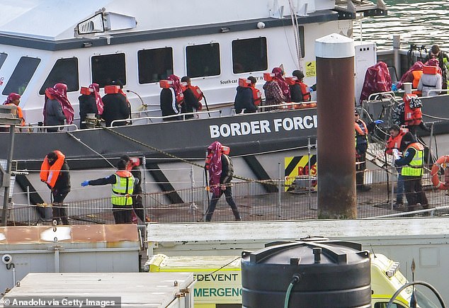 Border Force officers escort migrants into Dover Docks after helping them ashore