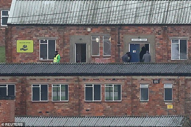 People enter a building at Crowborough army training camp, repurposed by the UK government as an accommodation centre for asylum seekers, in Crowborough, southern Britain, on Friday
