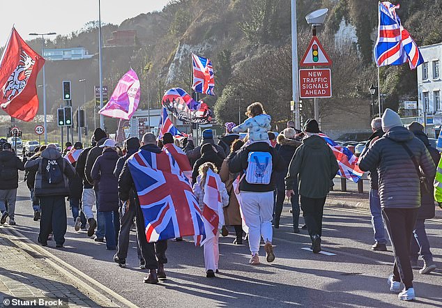 A group of people march while carrying Union Jack flags in Dover Kent today