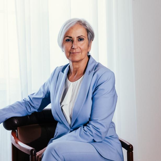 Anna Sporrer sitzt auf einem Stuhl vor einem Fenster.