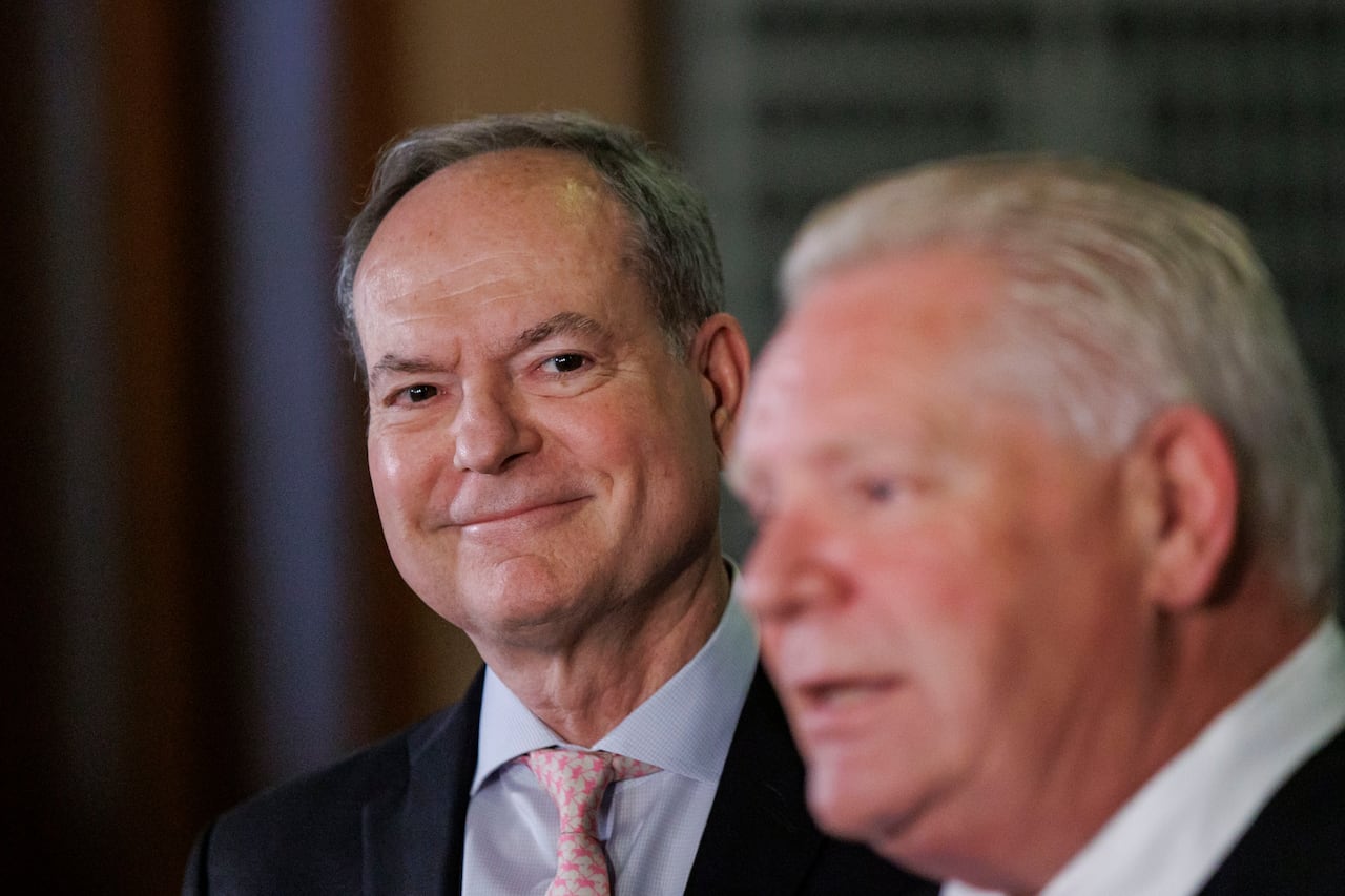 A man looks at another with a smile on his face.