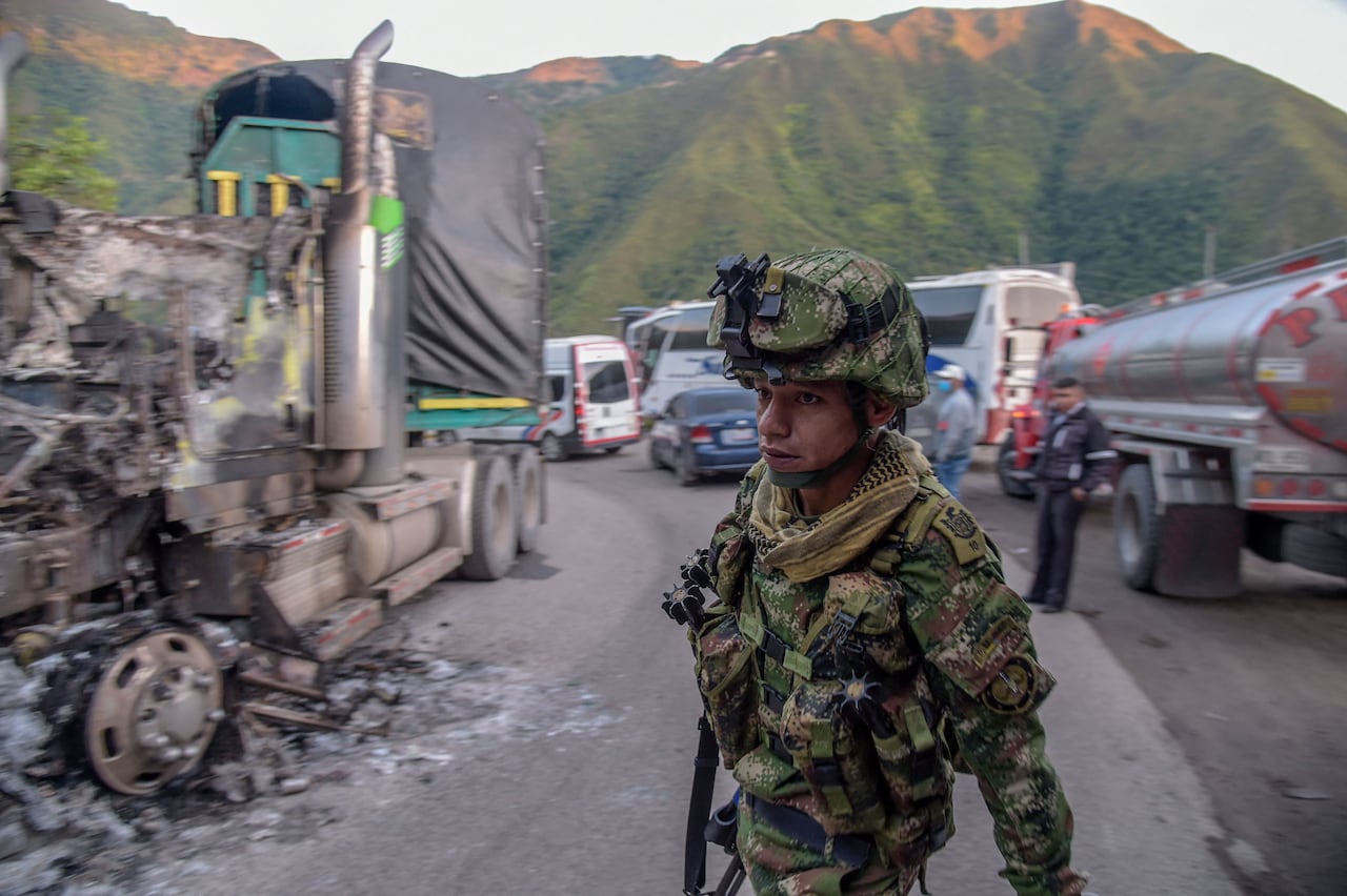 A soldier walks past a burnedout truck
