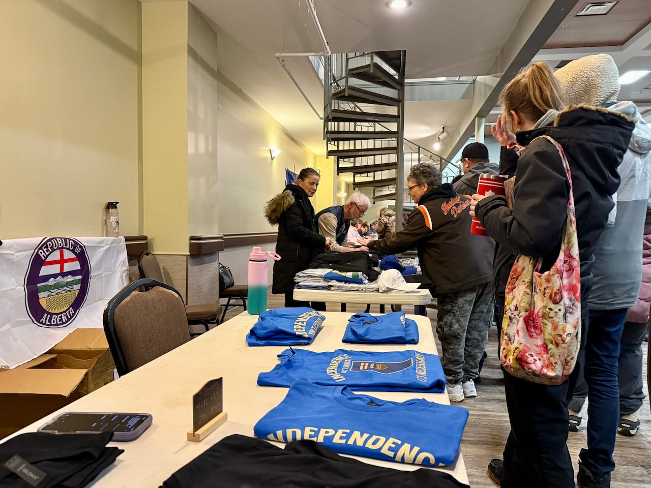 A few people checking out T-shirts and other things kept on a table.