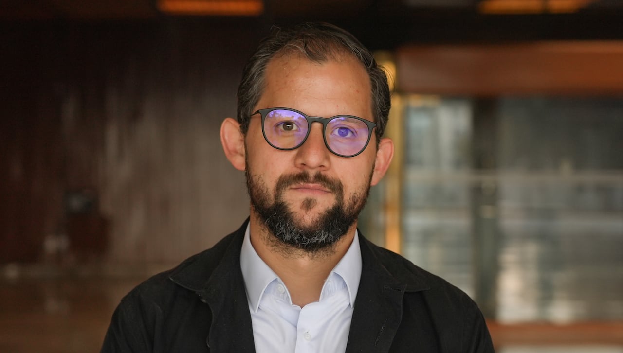 A man with glasses looks into the camera.