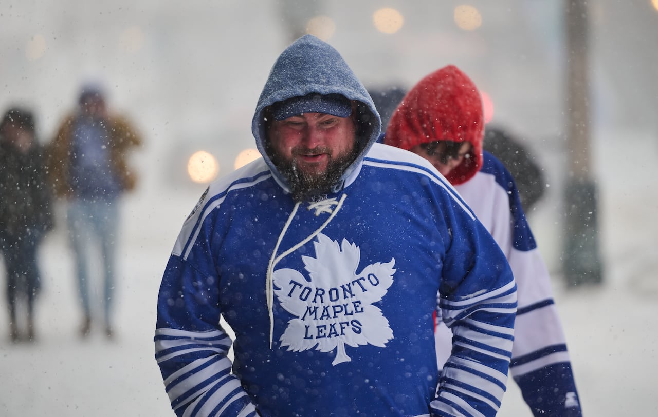 People wearing sports jerseys walk during a snow storm.