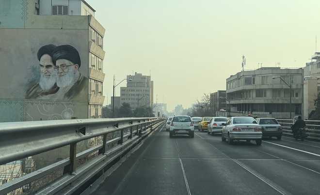 Vehicles drive past portrait of the late Iranian revolutionary founder Ayatollah Khomeini, left, and Supreme Leader Ayatollah Ali Khamenei, in downtown Tehran, Iran, Sunday, Jan. 25, 2026.